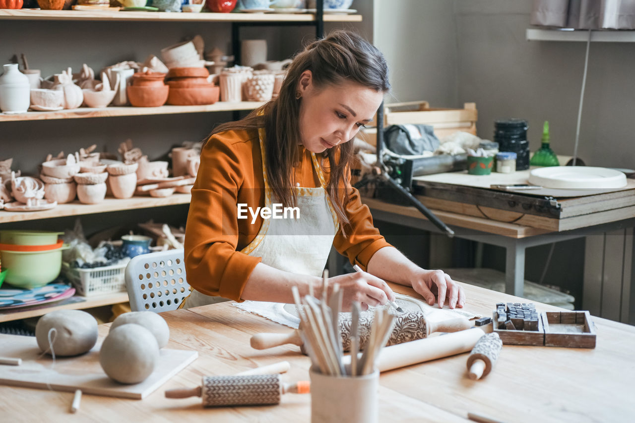 Middle-aged woman moulding a plate in a pottery studio