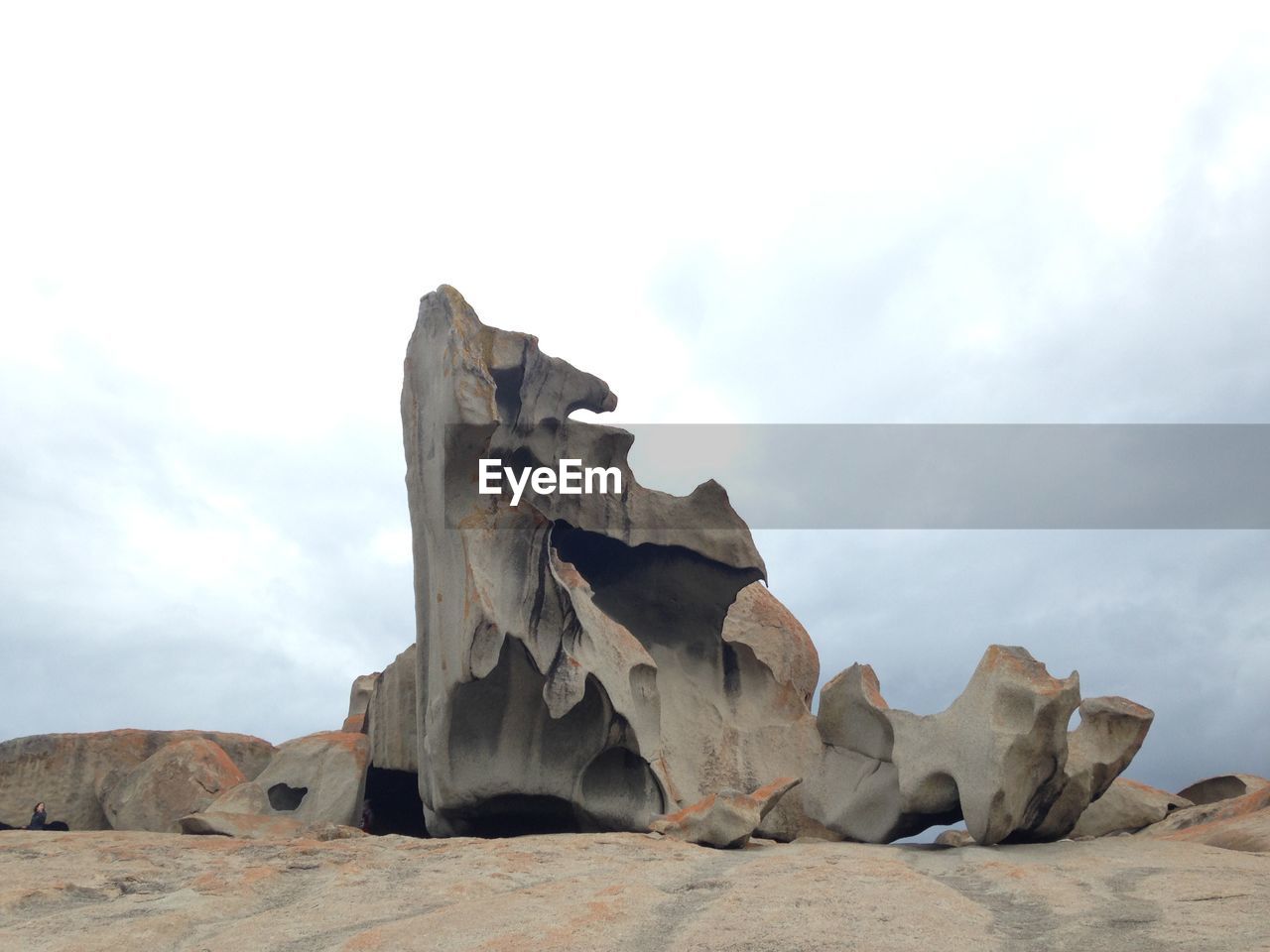 Low angle view of rocks against cloudy sky