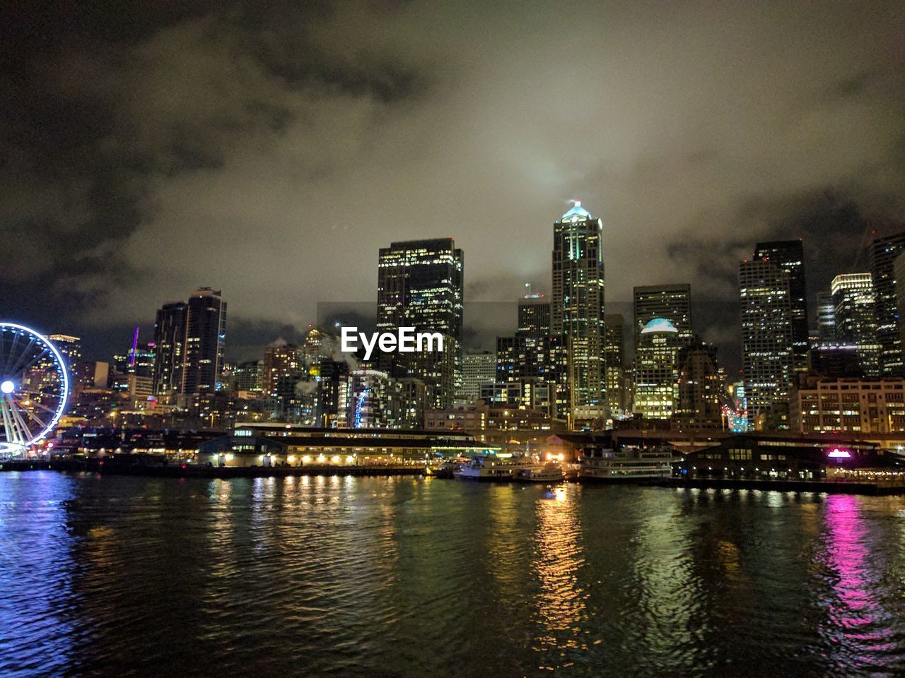 VIEW OF ILLUMINATED CITY AT WATERFRONT