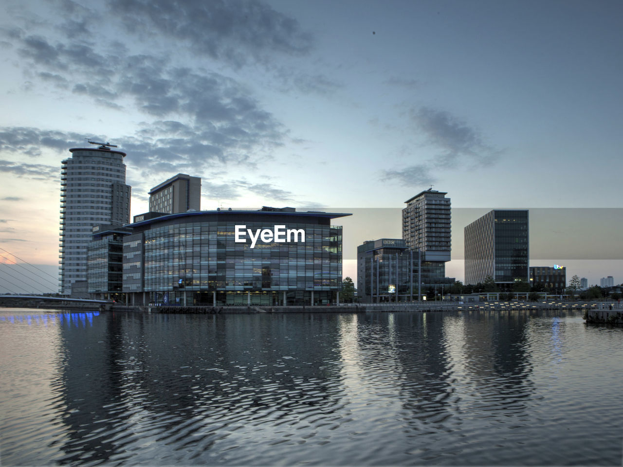 View of cityscape by river against sky