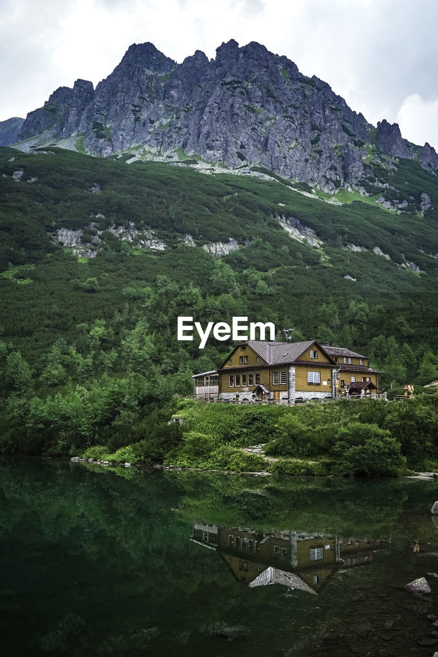 SCENIC VIEW OF LAKE BY BUILDING AGAINST MOUNTAIN