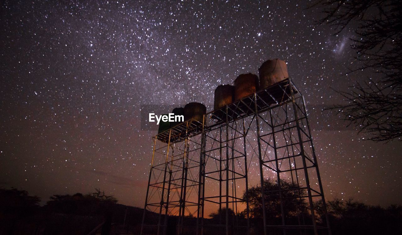 Low angle view of water tanks against sky at night