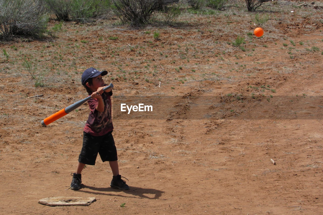 Full length of boy playing baseball on field
