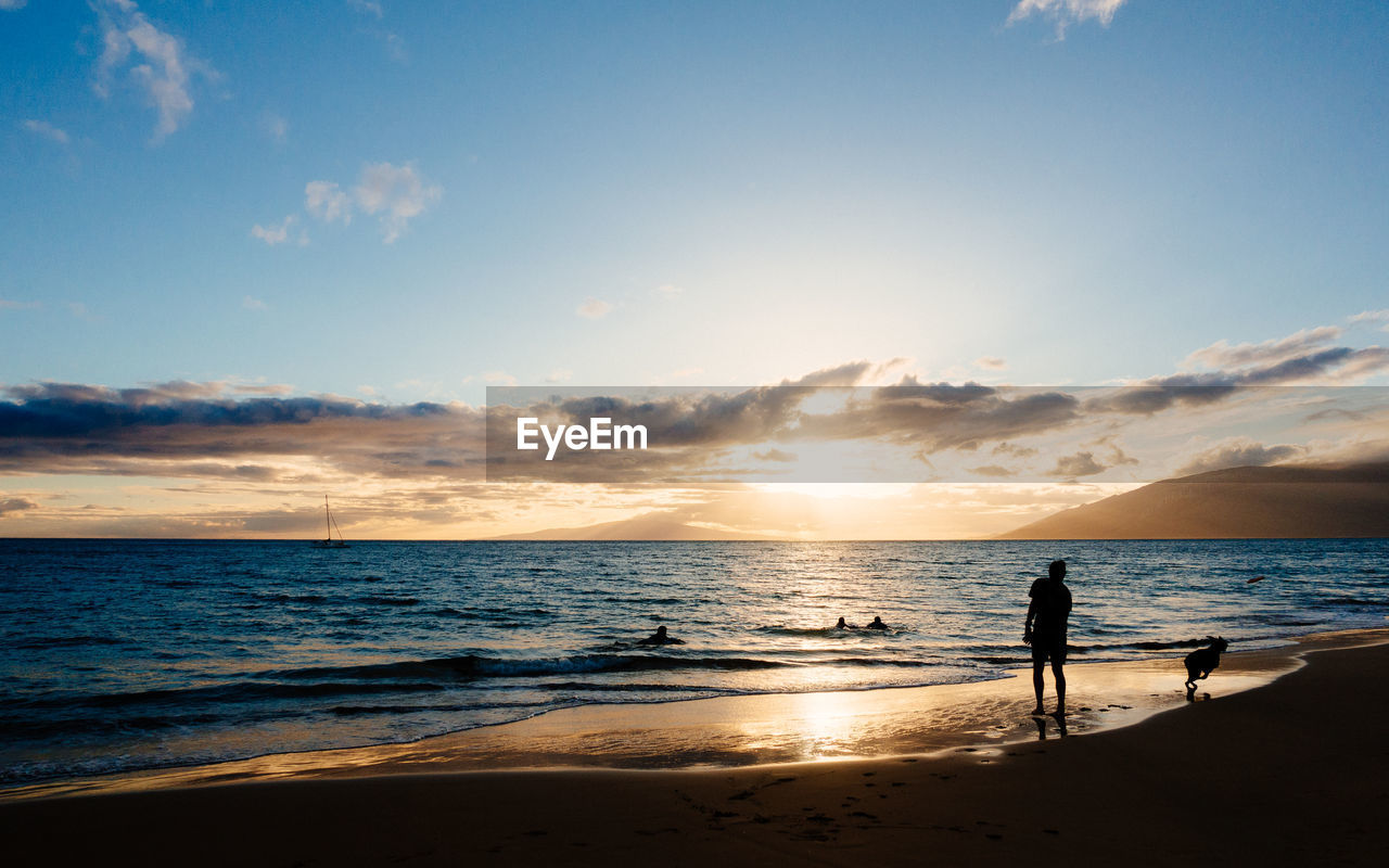 Scenic view of beach against cloudy sky during sunset