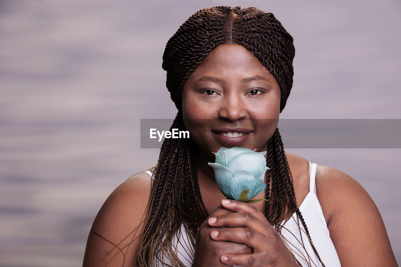 portrait of young woman holding ice cream cone against sky during sunset