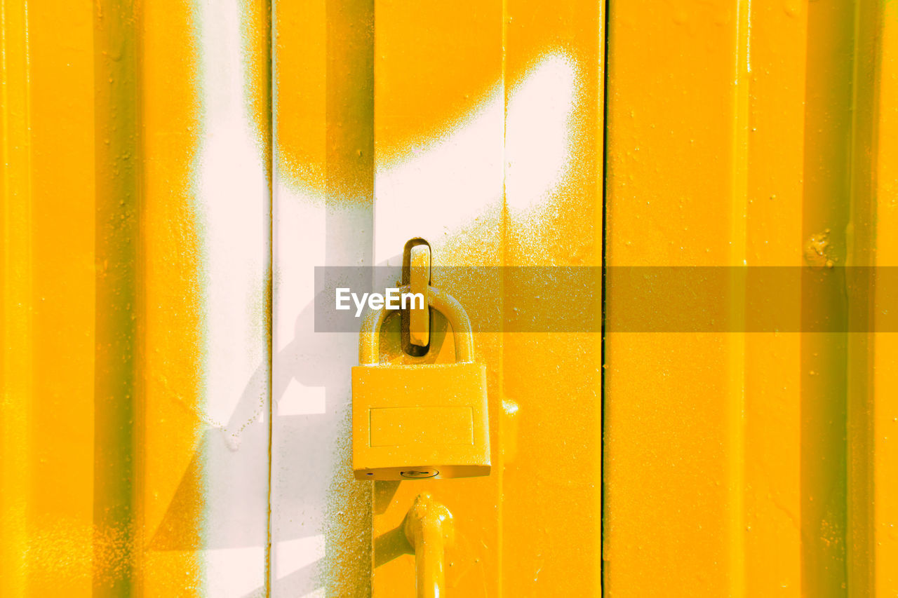 Yellow padlock on yellow and white door