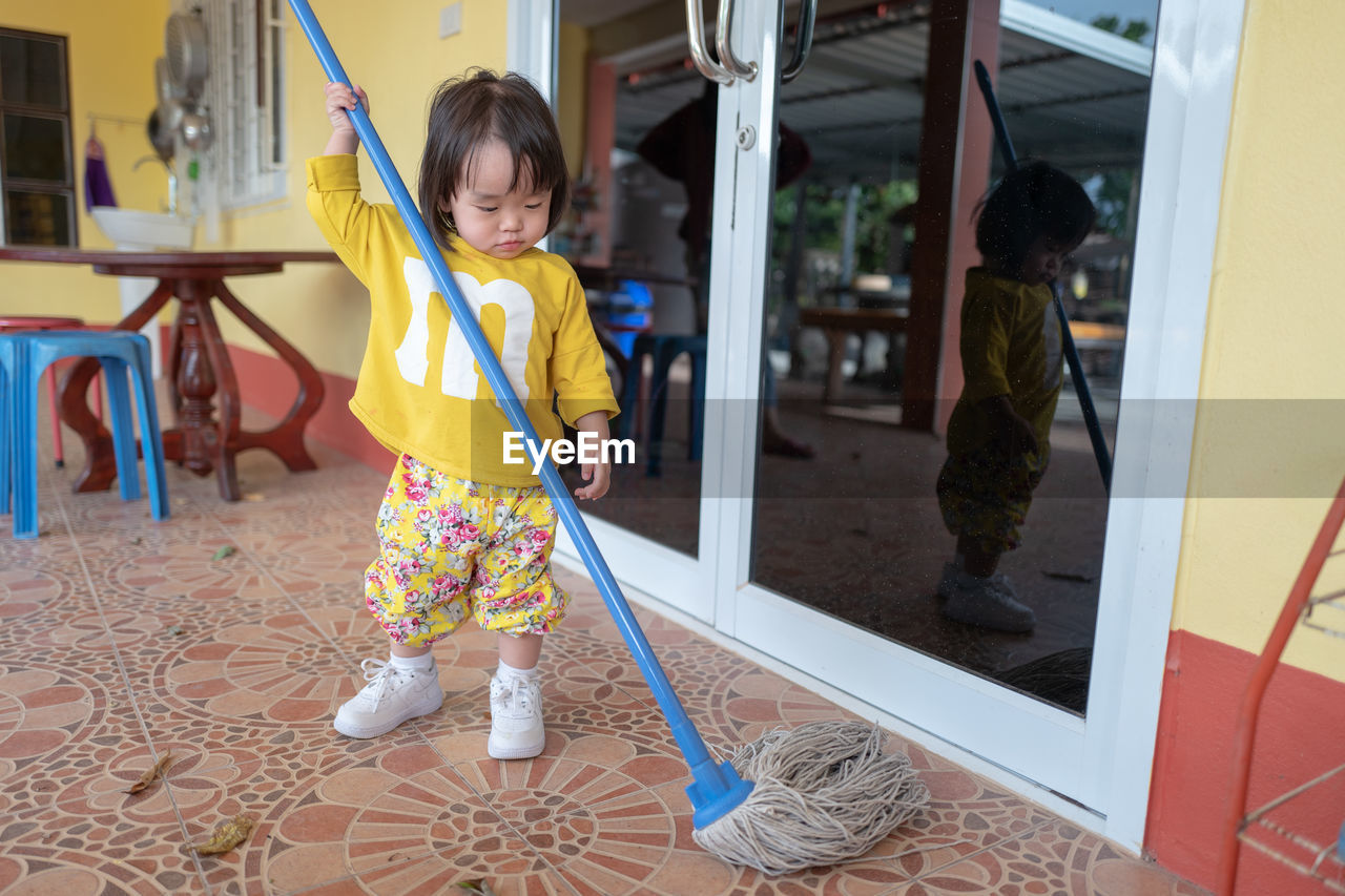 Cute baby girl moping floor at home