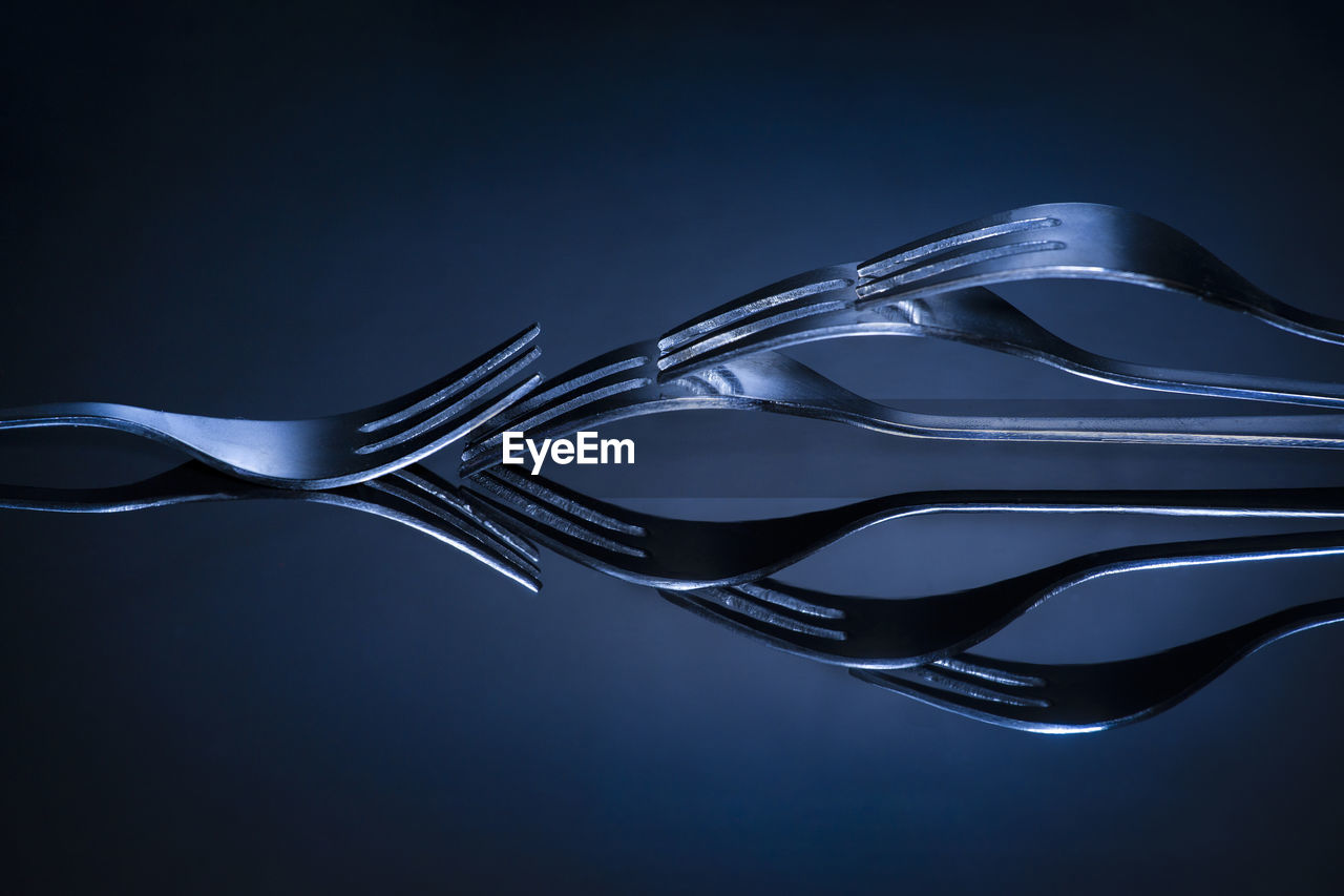 Close-up of forks arranged on table against blue background