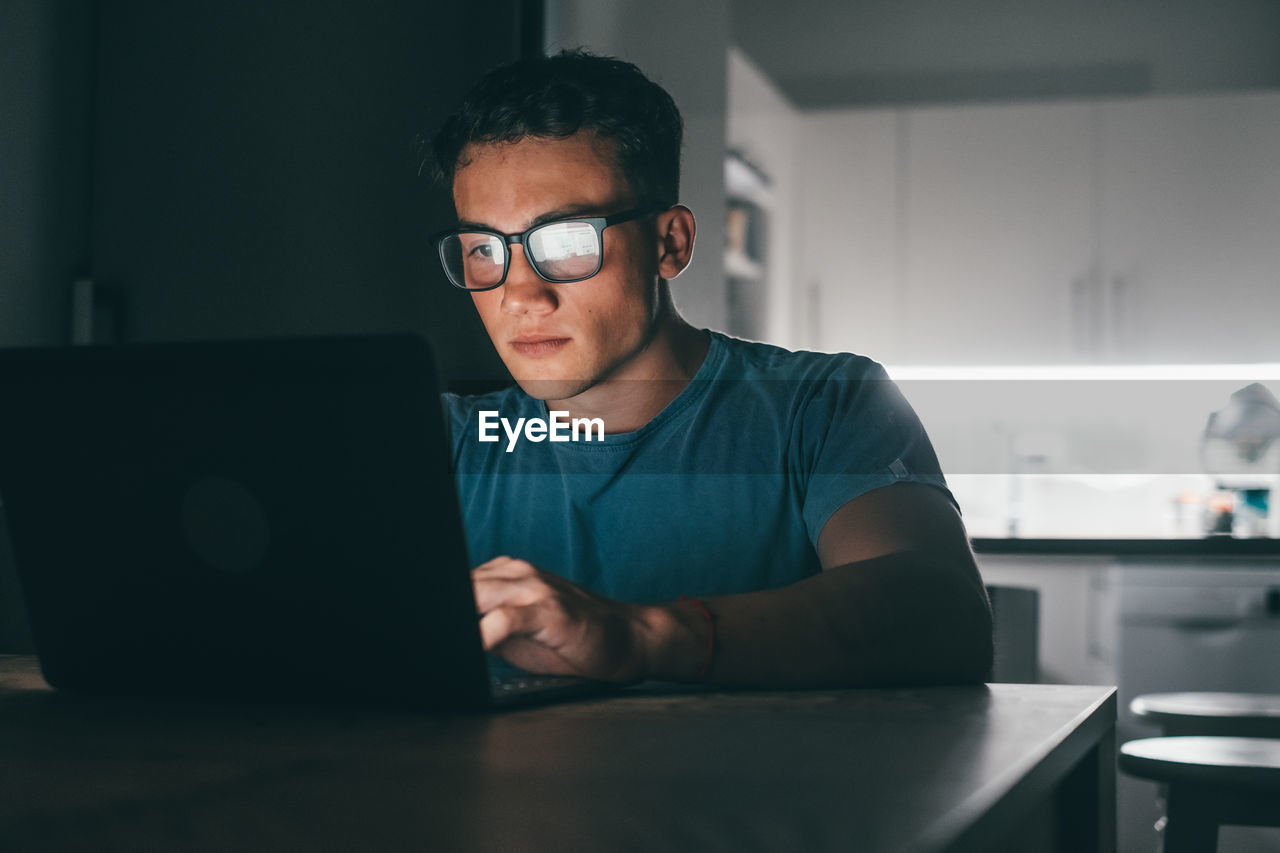 portrait of young man using laptop at desk