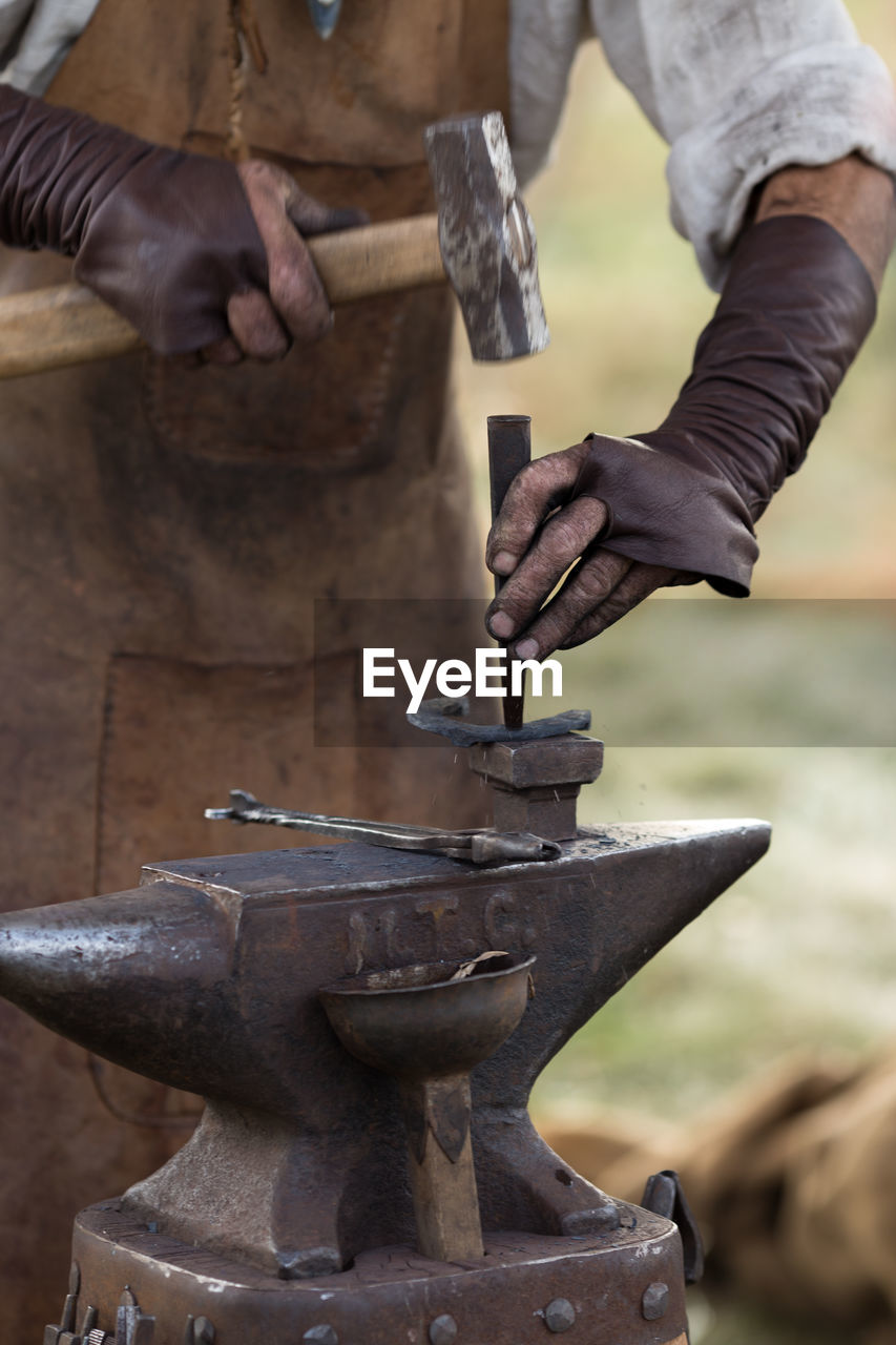 Midsection of blacksmith working at workshop