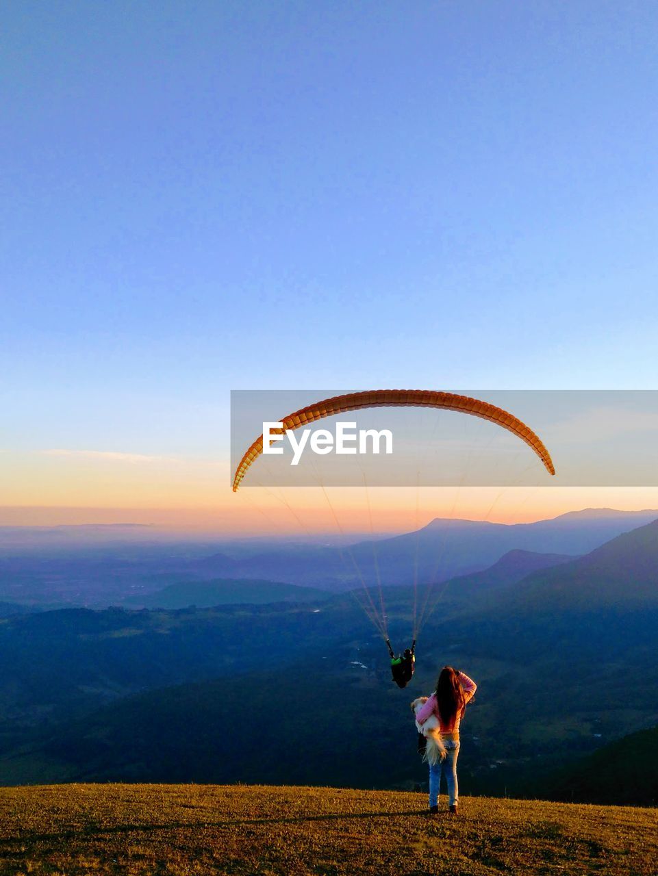 Woman looking at person paragliding against sky