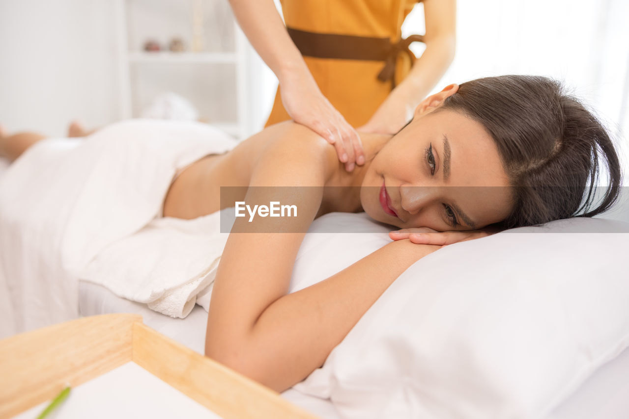 In a spa salon, a young woman enjoys massage therapy.