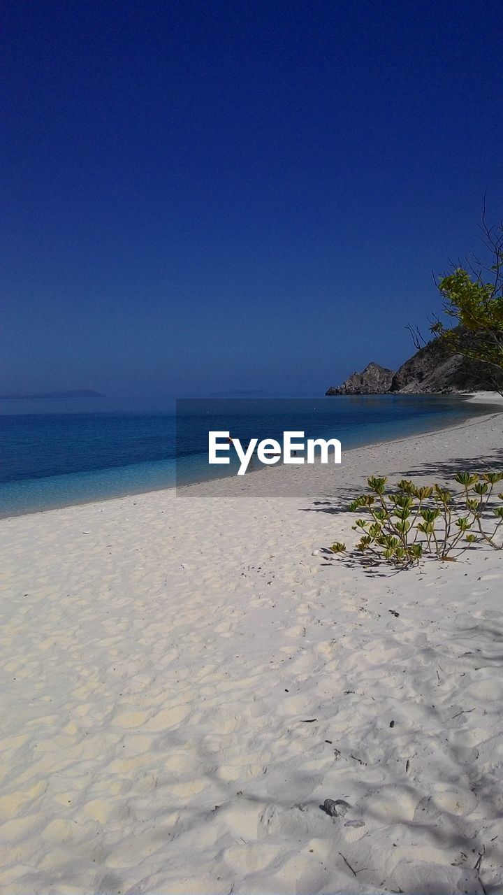 Scenic view of beach against clear blue sky