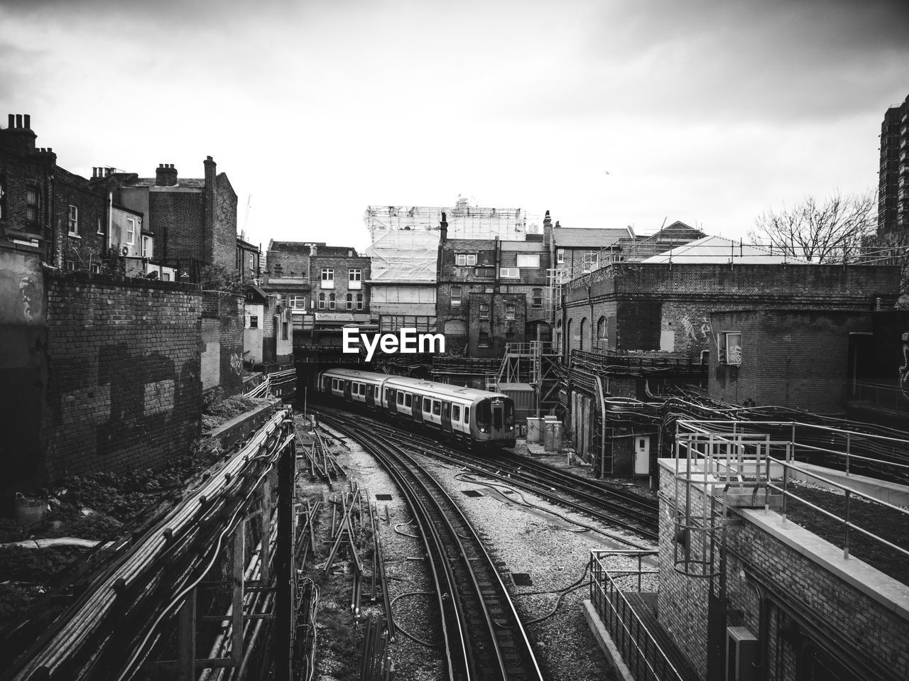 HIGH ANGLE VIEW OF RAILROAD TRACKS BY BUILDINGS AGAINST SKY