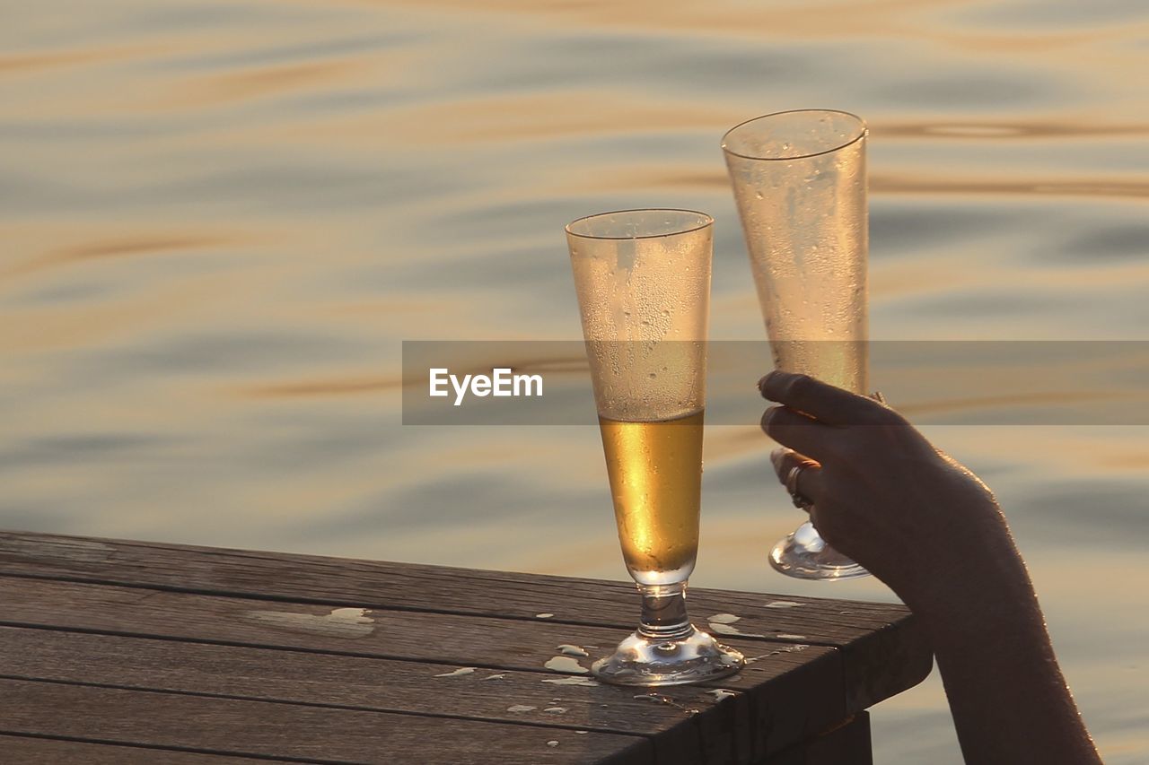 Beer glass and hand by water