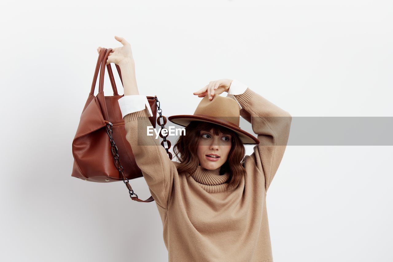 Young woman holding bag against white background