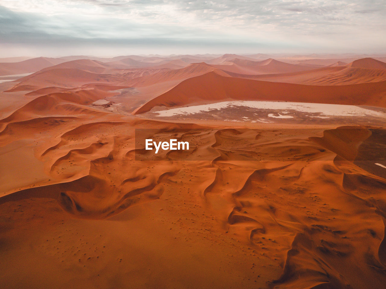 Scenic view of desert against cloudy sky