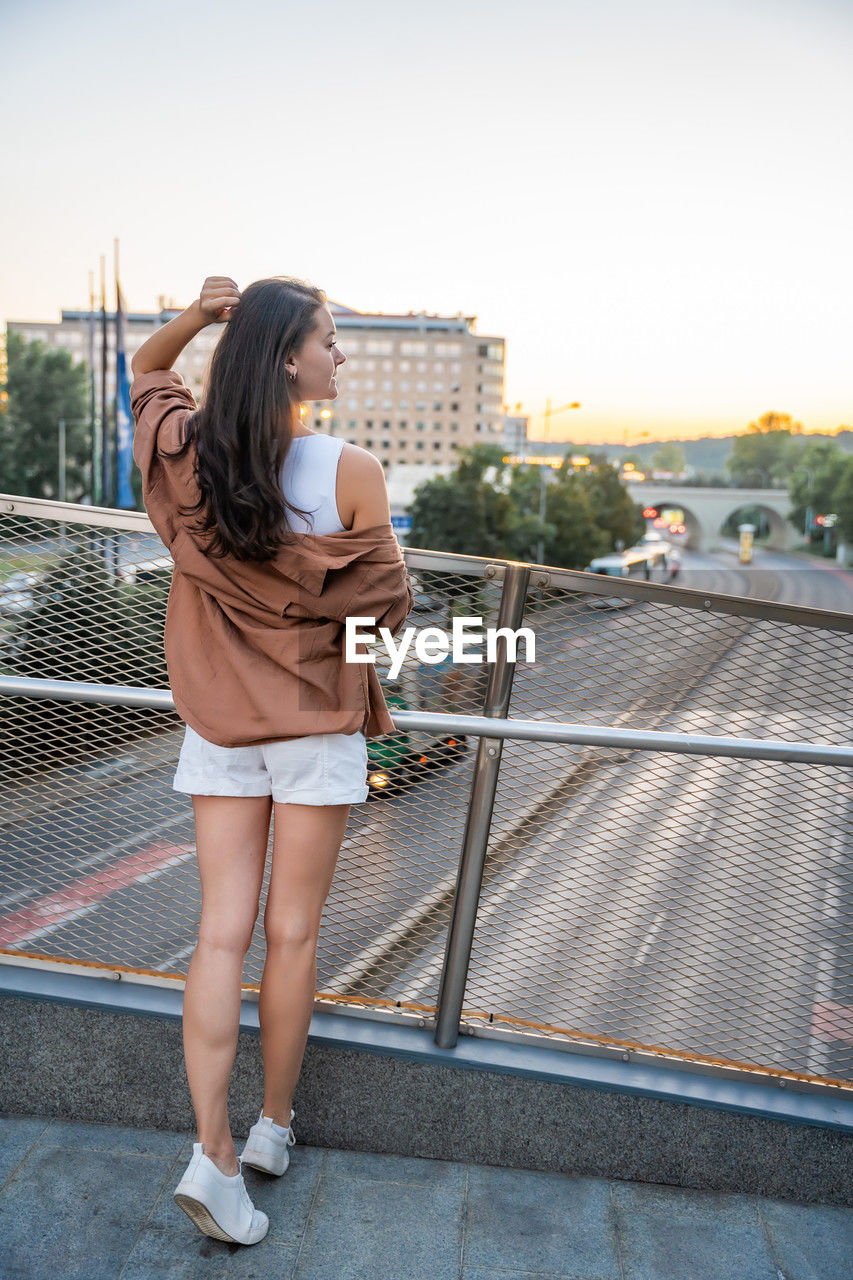 side view of young woman standing on railing