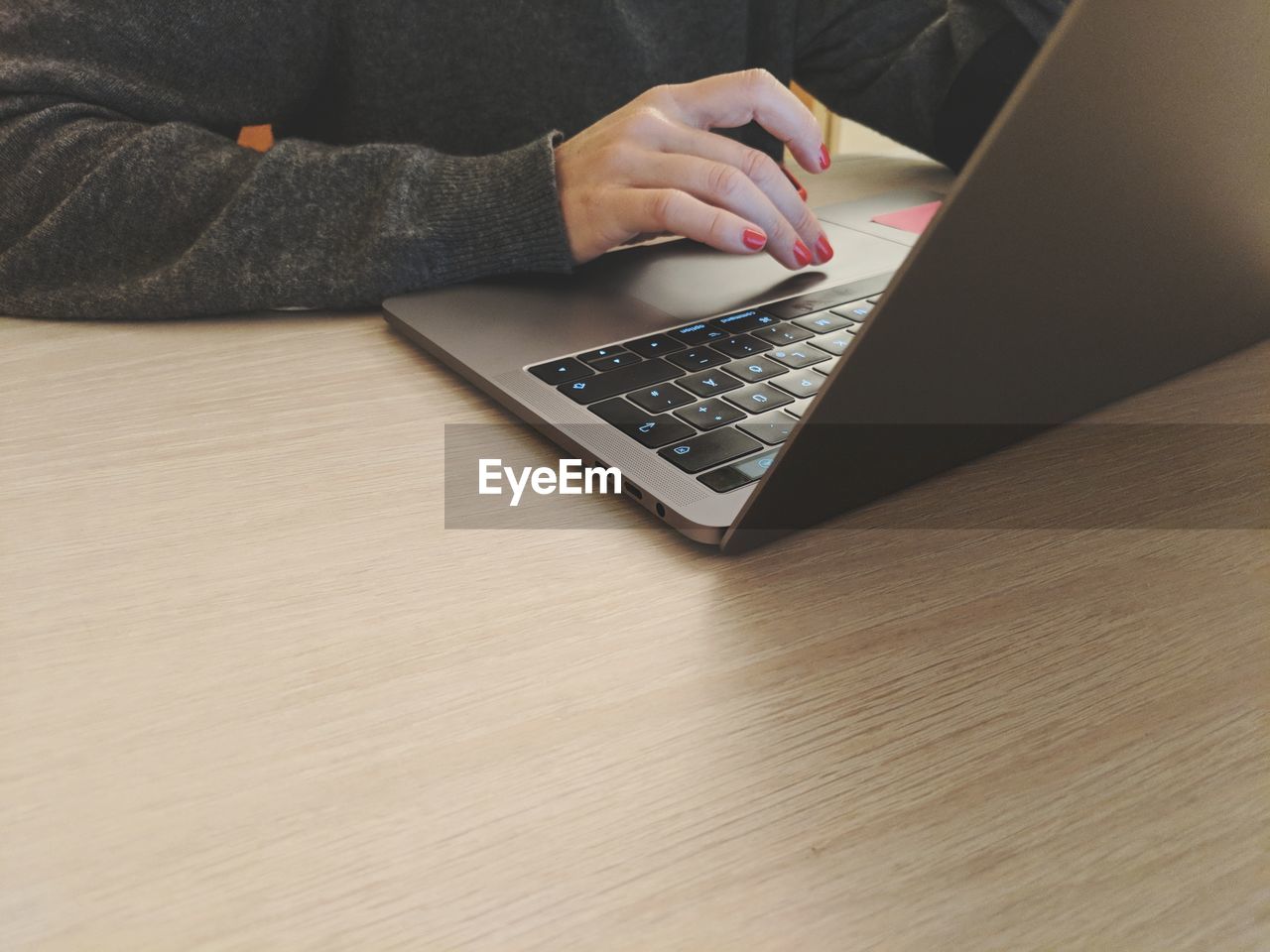 Midsection of woman using laptop at table