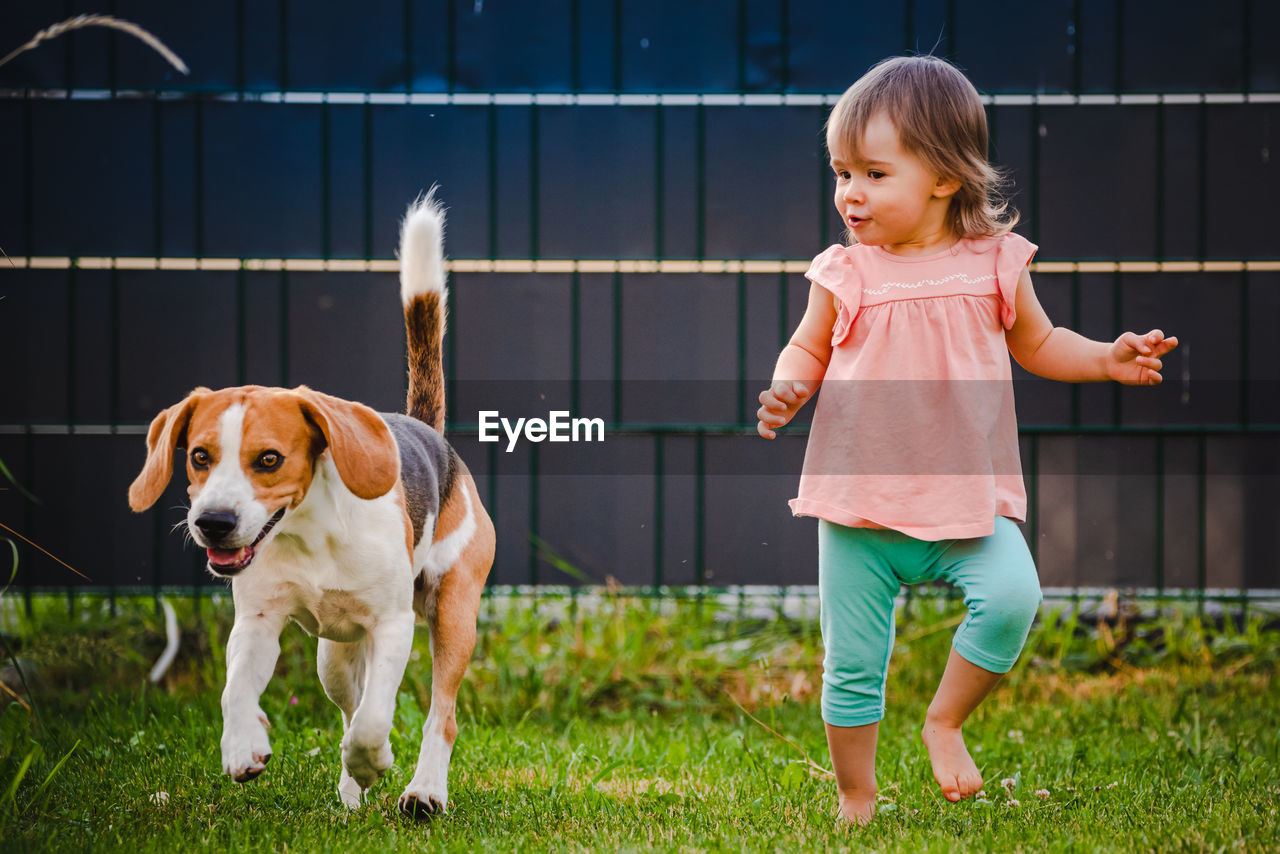 Cute girl and dog against fence at back yard