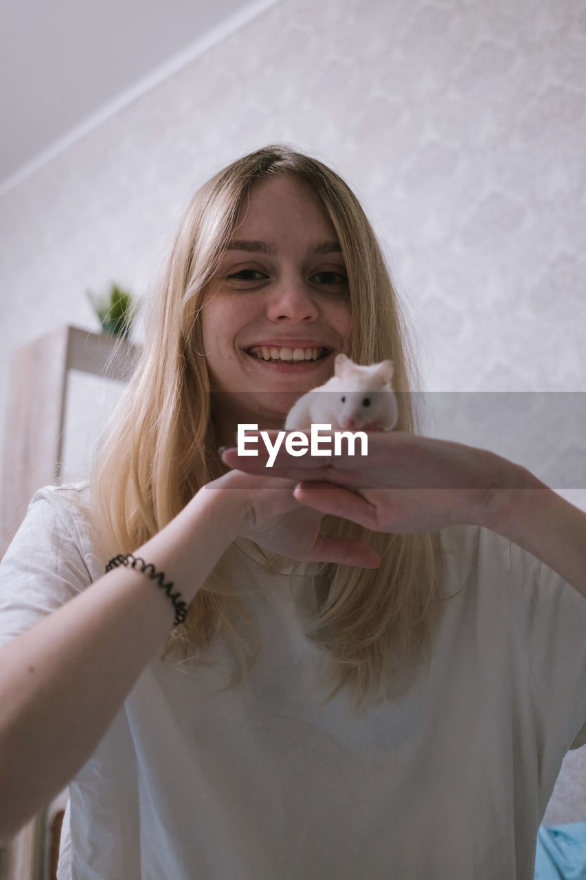 Happy girl with a small white syrian hamster. friendship between human and animal. 