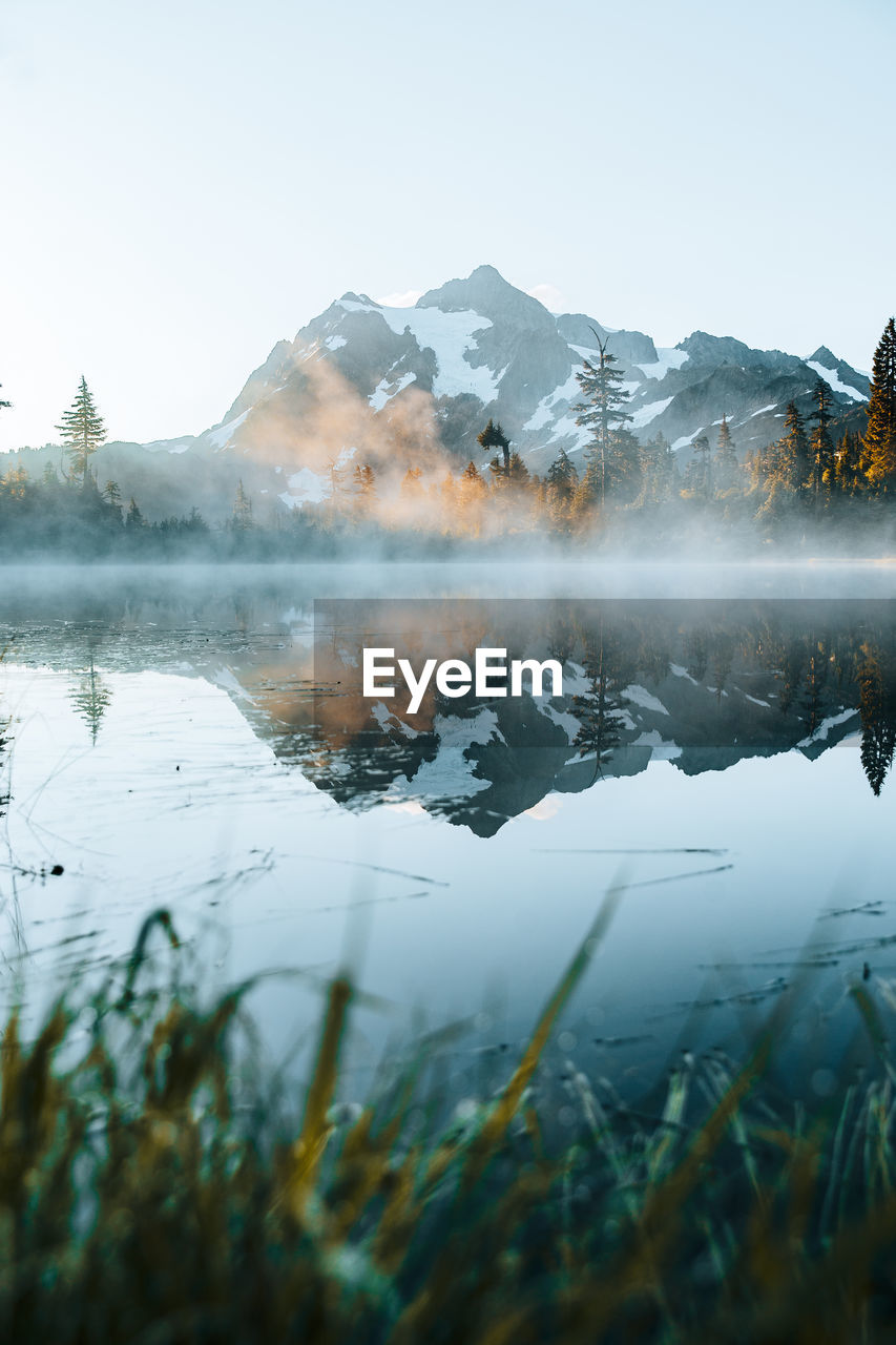 Scenic view of lake by snowcapped mountains against sky