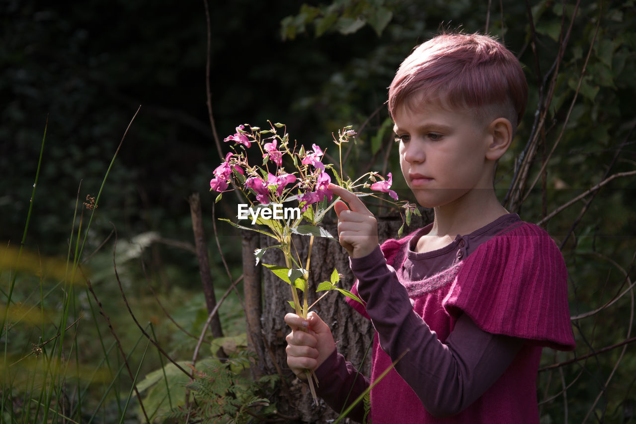 Cute girl holding pink flowering plants