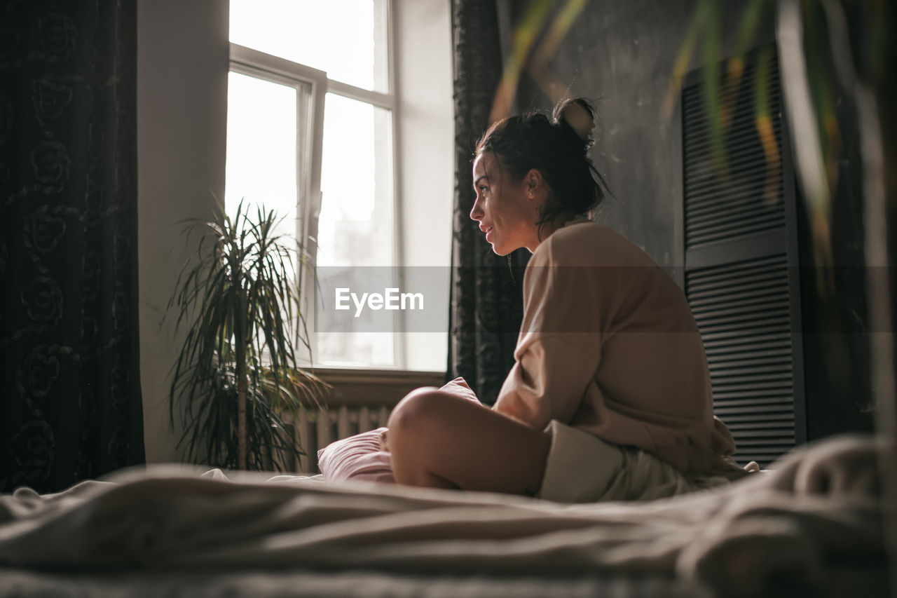 Woman sitting on bed at home