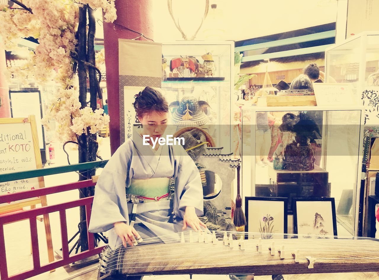 PORTRAIT OF WOMAN STANDING BY STORE