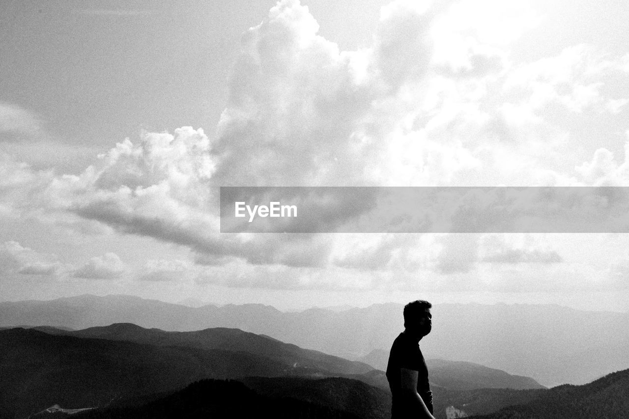 REAR VIEW OF WOMAN STANDING ON MOUNTAIN