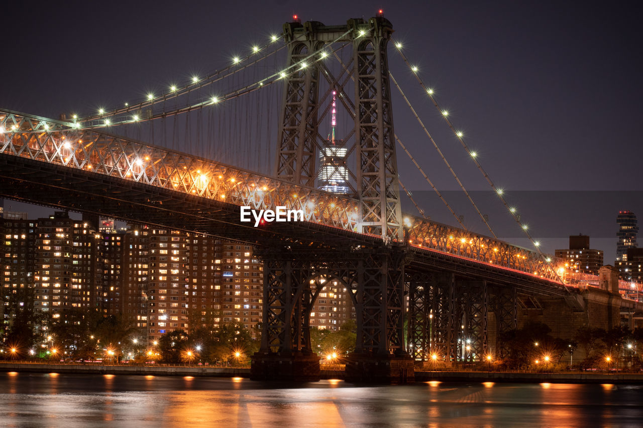 Illuminated bridge over river at night