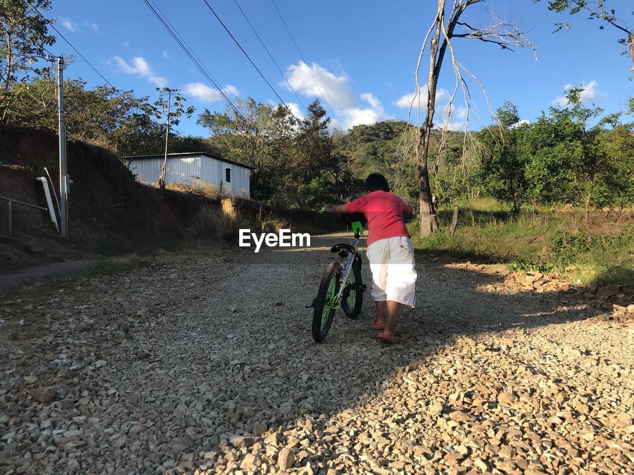 MAN WALKING ON ROAD AGAINST TREES