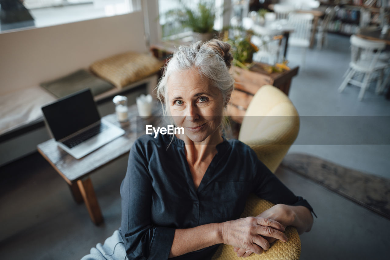 Smiling businesswoman sitting on chair at coffee shop