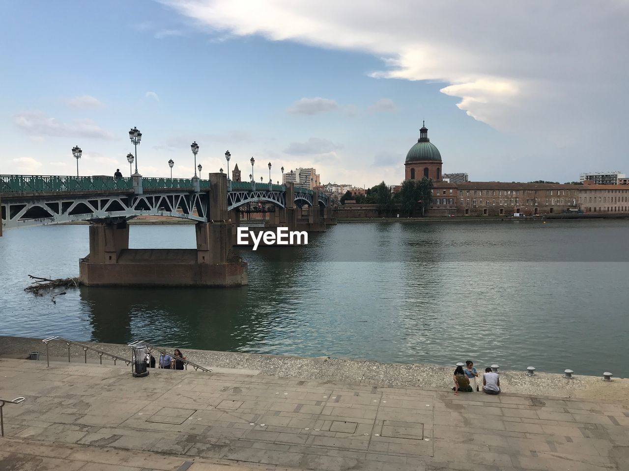 PEOPLE IN RIVER BY BUILDING AGAINST SKY