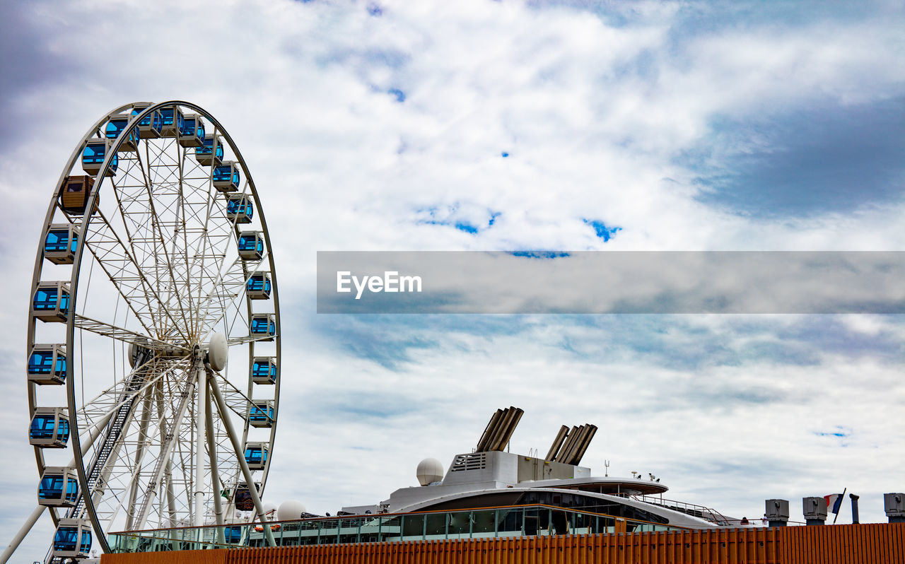 Low angle view of ferris wheel against cloudy sky