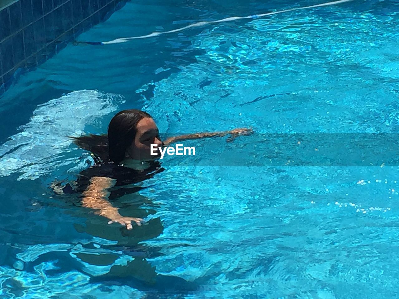 HIGH ANGLE VIEW OF WOMAN SWIMMING UNDERWATER IN POOL