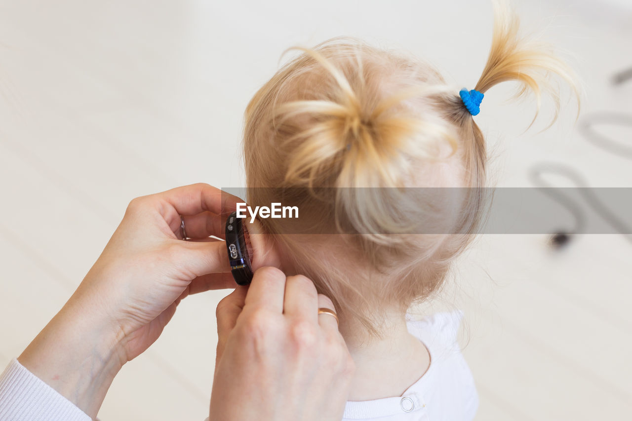 Close-up of mother adjusting hearing aid of daughter