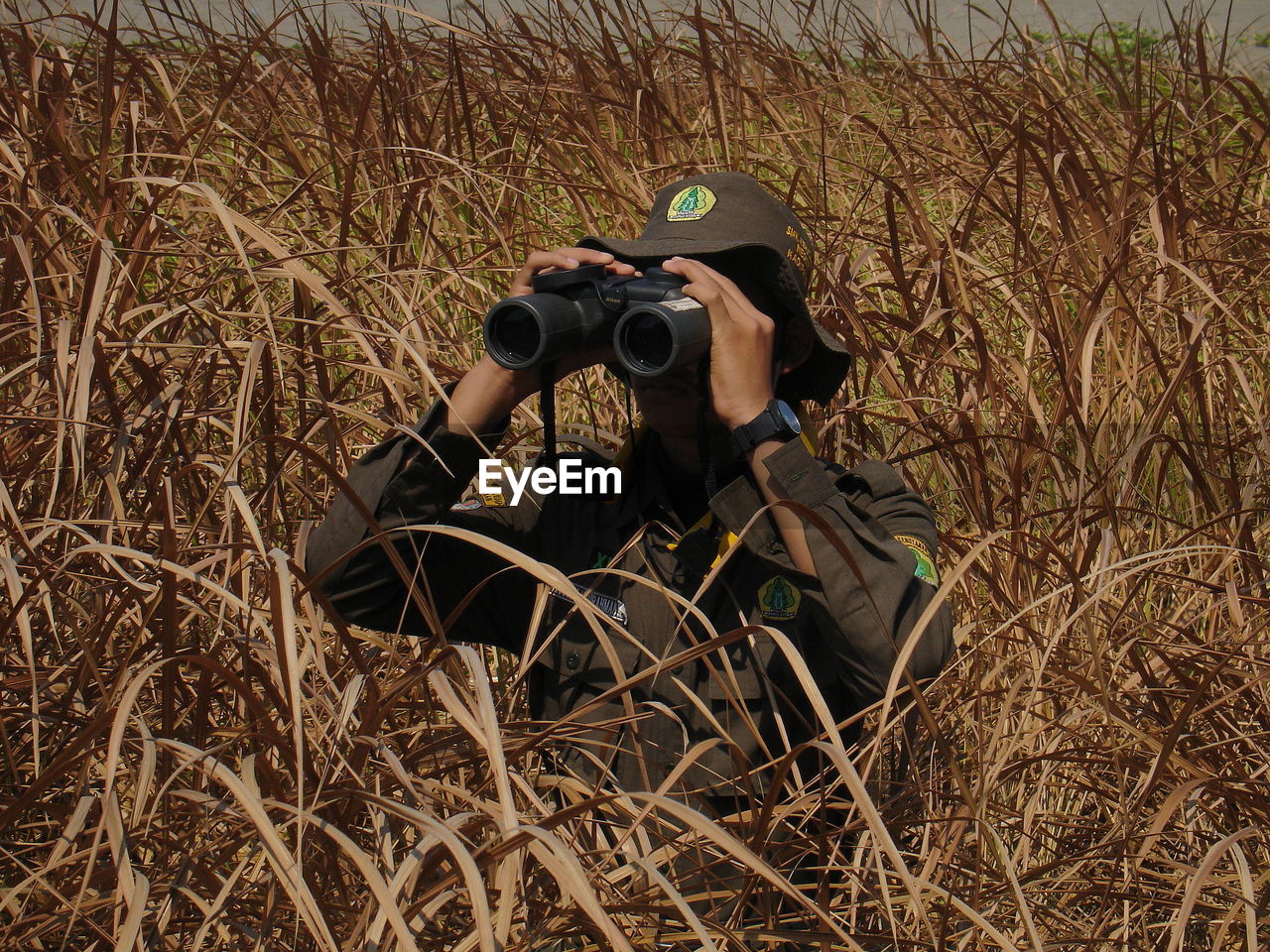 MAN PHOTOGRAPHING WITH CAMERA ON FIELD