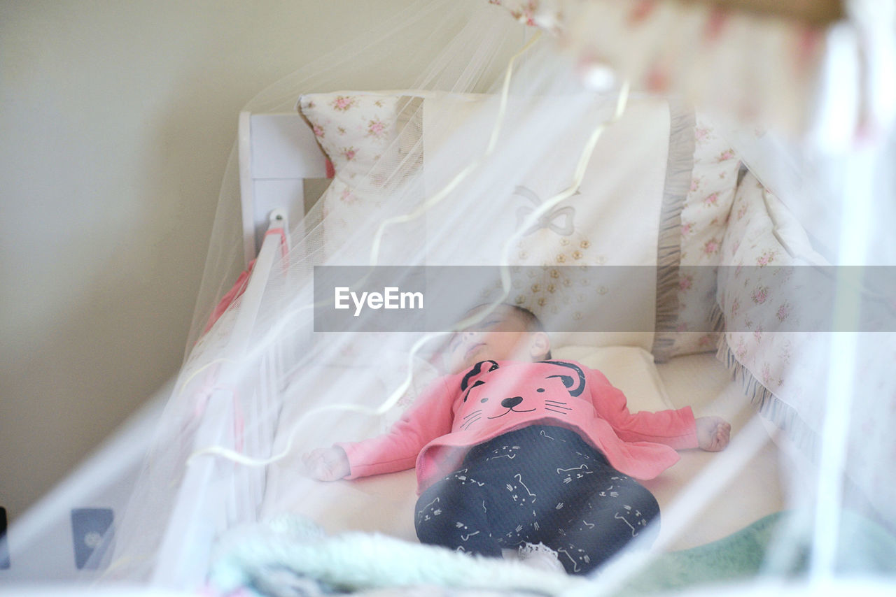 Cute baby girl sleeping in crib at home