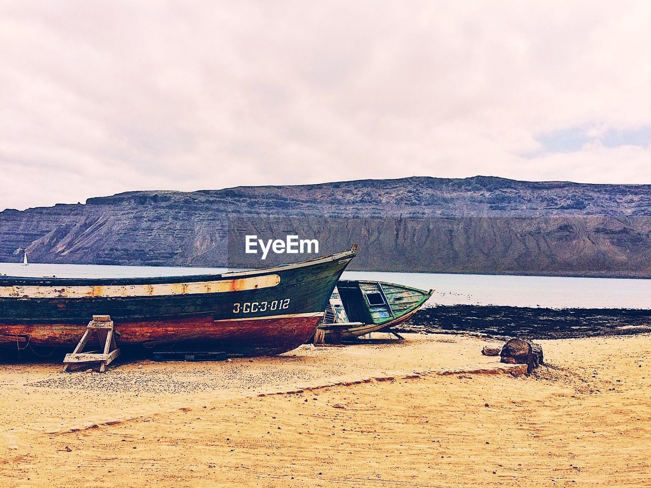 BOAT MOORED ON SHORE AGAINST SKY