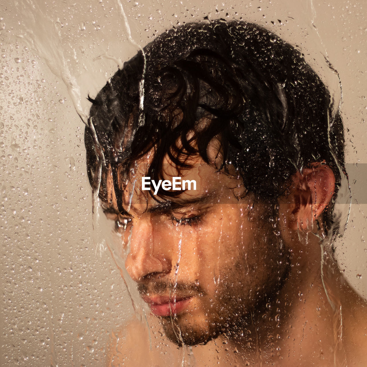 Close-up of thoughtful man taking shower in bathroom