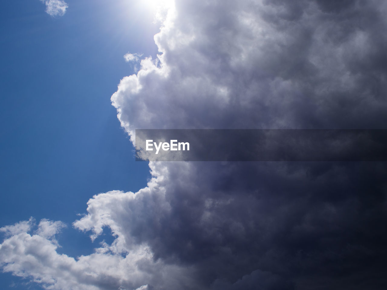 Low angle view of sunlight streaming through clouds with silver lining