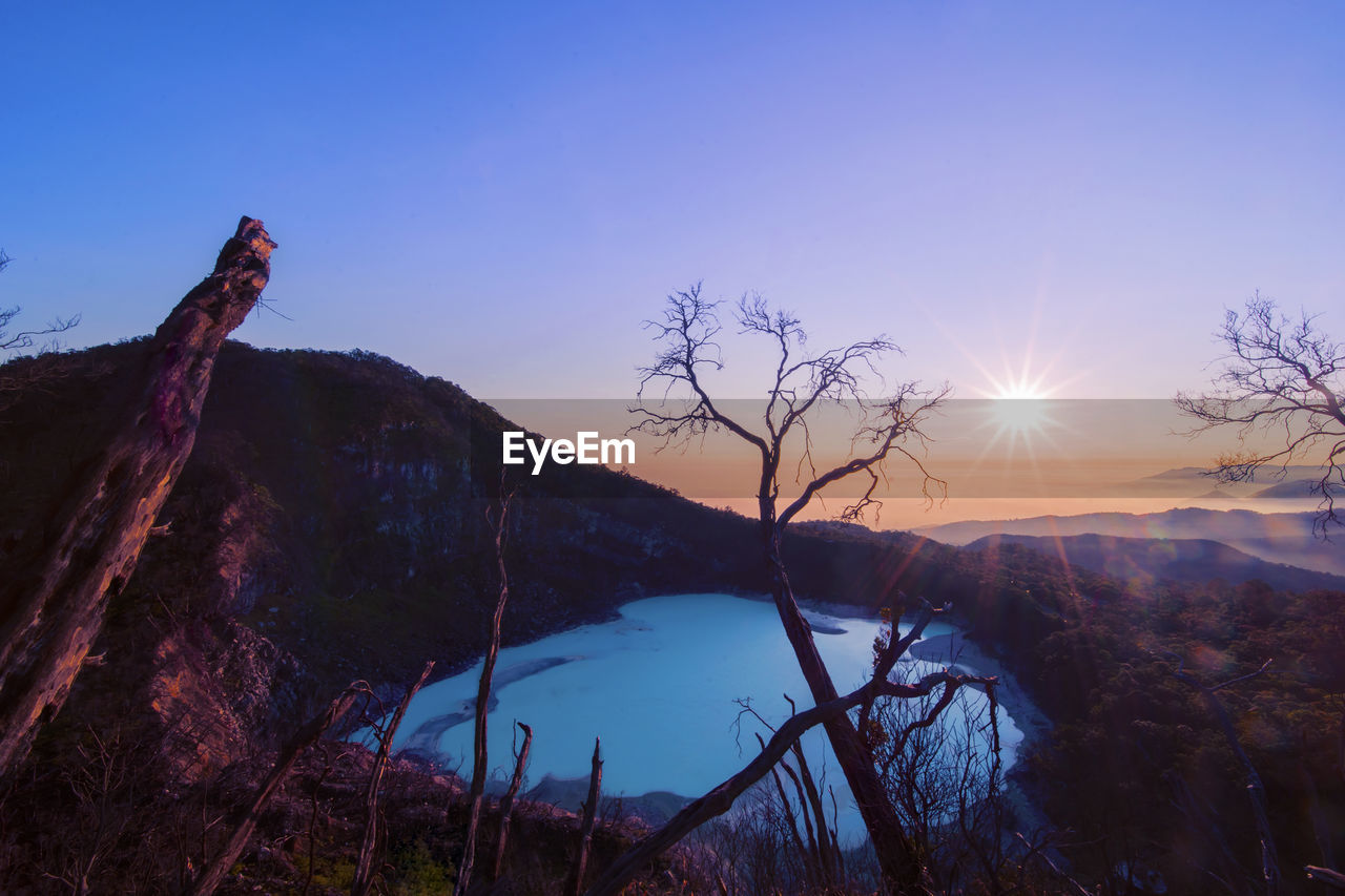 SCENIC VIEW OF TREE AND MOUNTAINS AGAINST SKY DURING SUNSET