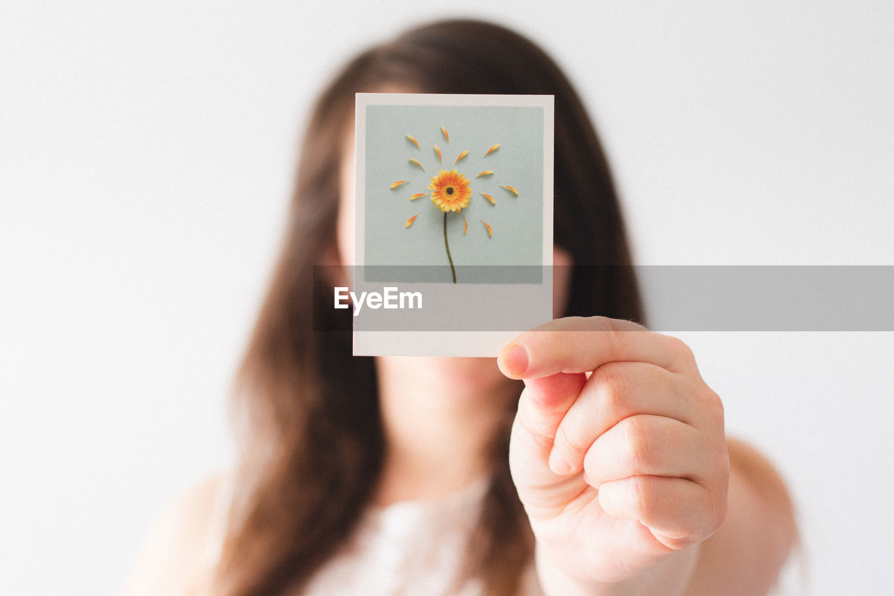 Close-up of woman holding picture against white background