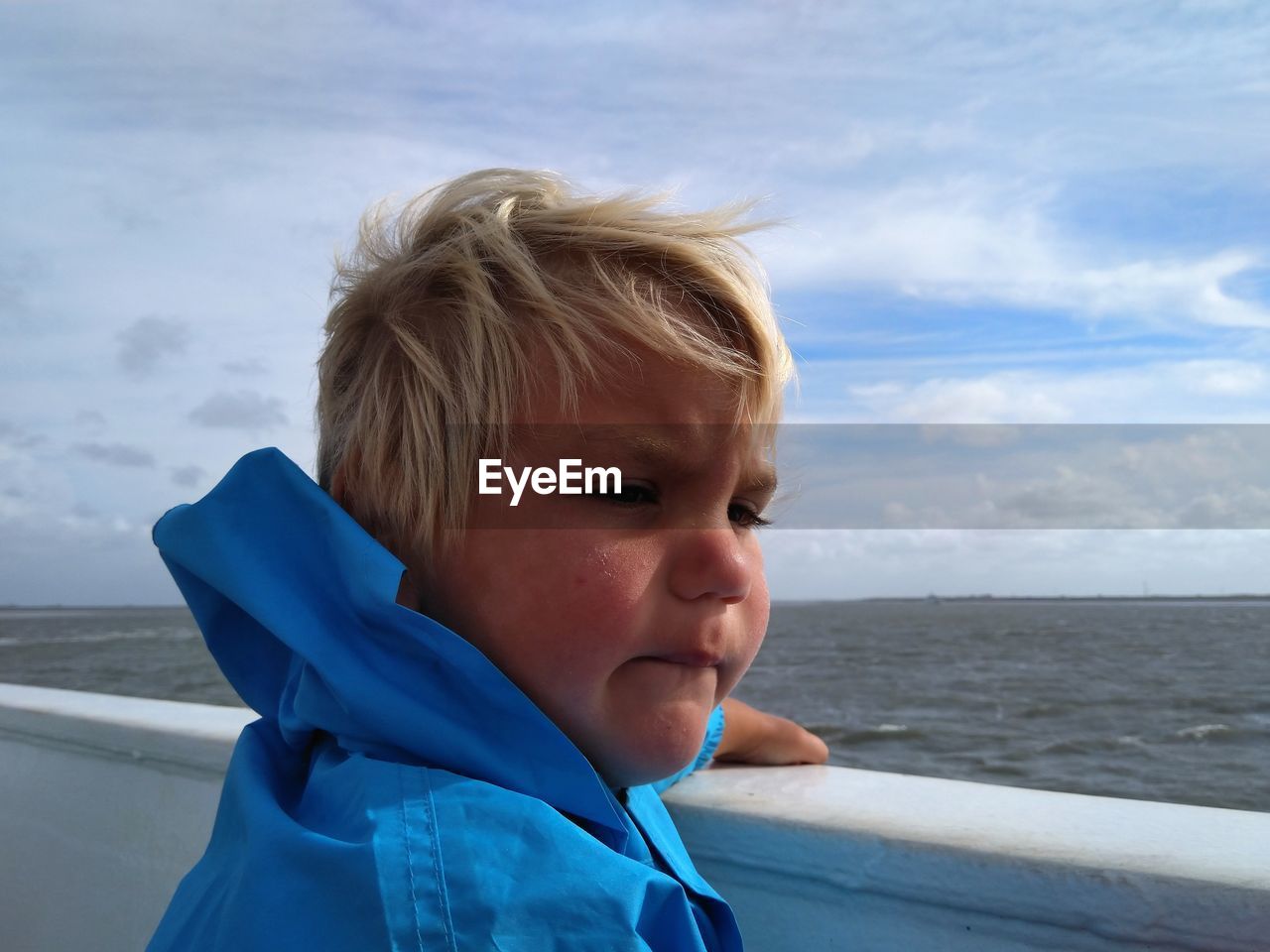 blue, childhood, child, water, sea, blond hair, men, one person, vacation, sky, portrait, headshot, cloud, nature, toddler, day, person, leisure activity, trip, looking, emotion, holiday, horizon, beach, horizon over water, nautical vessel, outdoors, travel, transportation, land, smiling, clothing, human face, looking away, side view, lifestyles