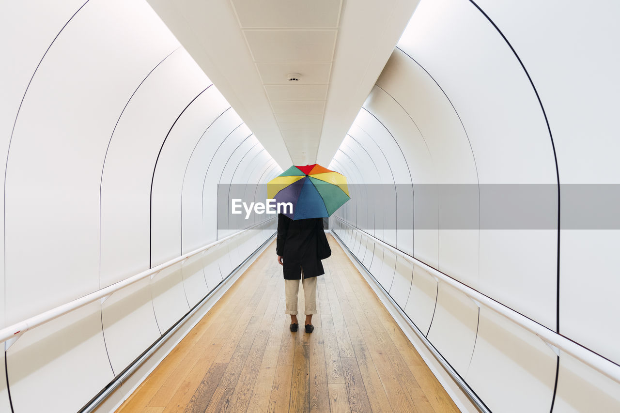 Young woman with umbrella standing on walkway