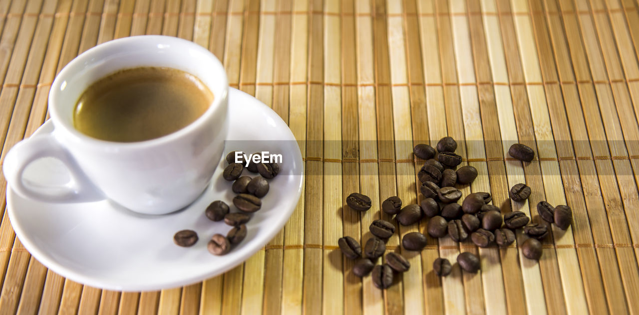 HIGH ANGLE VIEW OF COFFEE CUP ON WOODEN TABLE