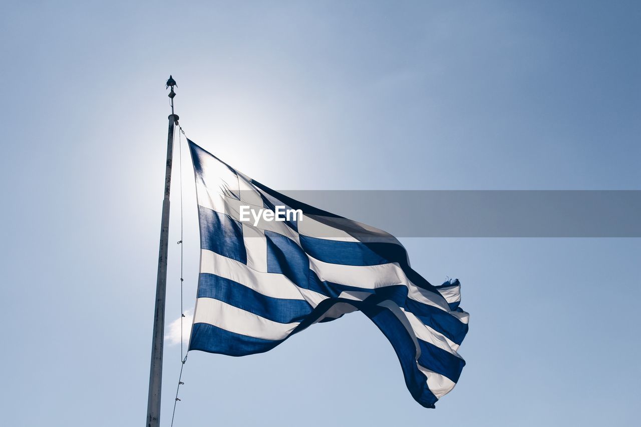 Low angle view of greek flag against clear blue sky during sunny day