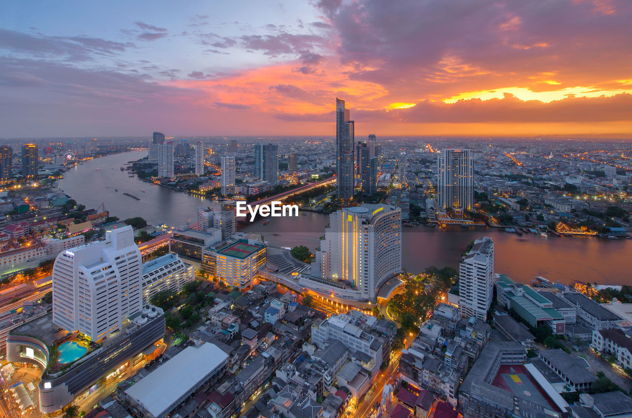 Illuminated cityscape against sky during sunset