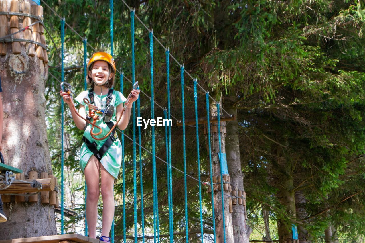 Adventure climbing high wire park - people on course in mountain helmet and safety equipment